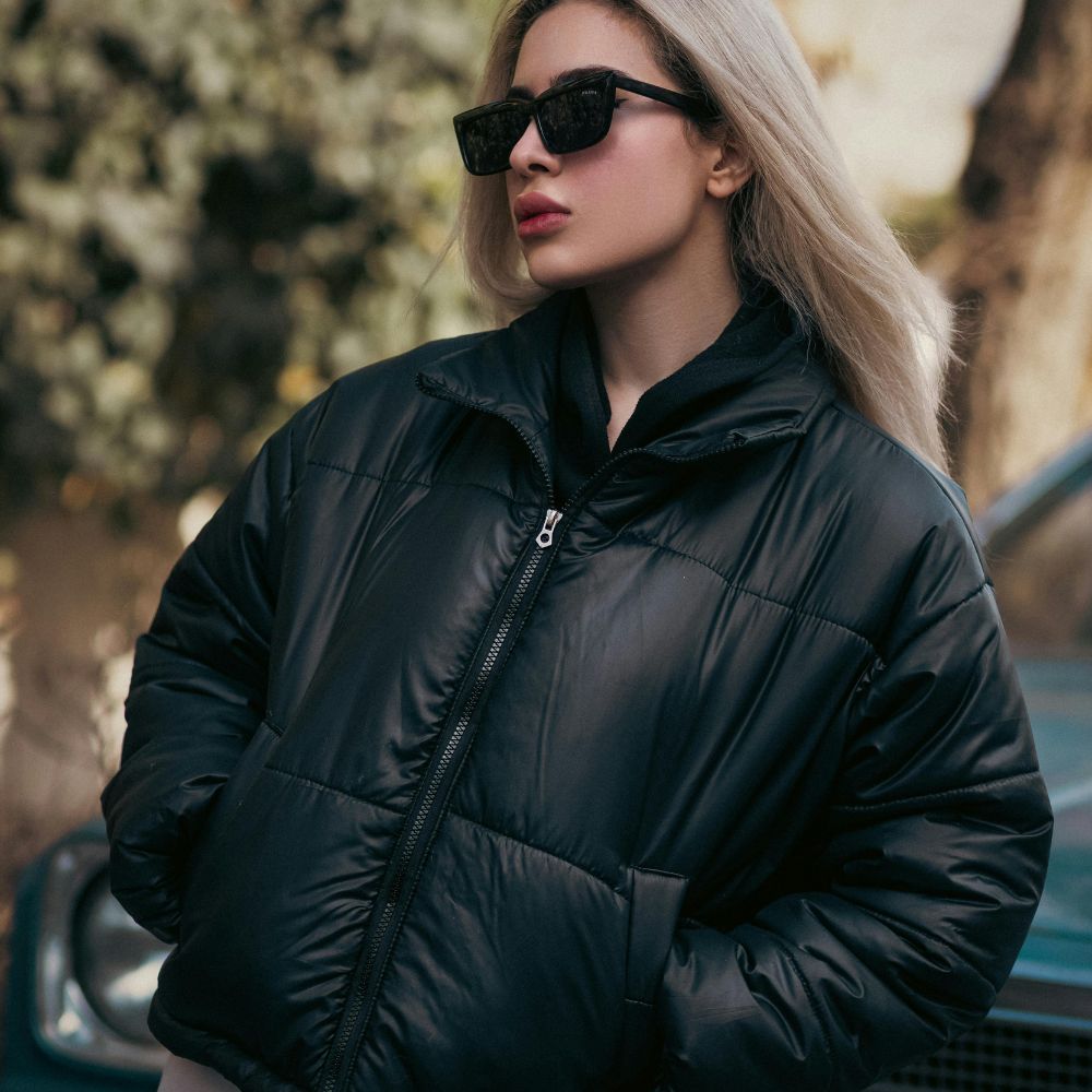 Woman wearing a black puffer jacket and sunglasses outdoors